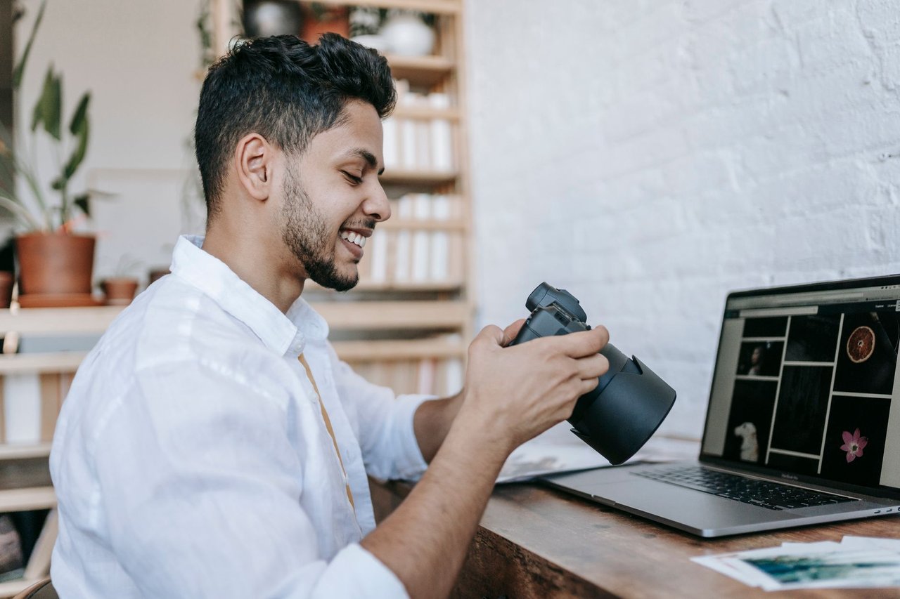 Fotógrafo sonriendo mientras arma un álbum de fotos en su computadora