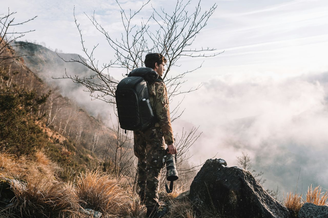 Fotógrafo en la cima de una montaña con niebla, ubicado en el tercio derecho de la imagen con amplio espacio negativo, ejemplo de regla de los tercios y espacio negativo en composición fotográfica
