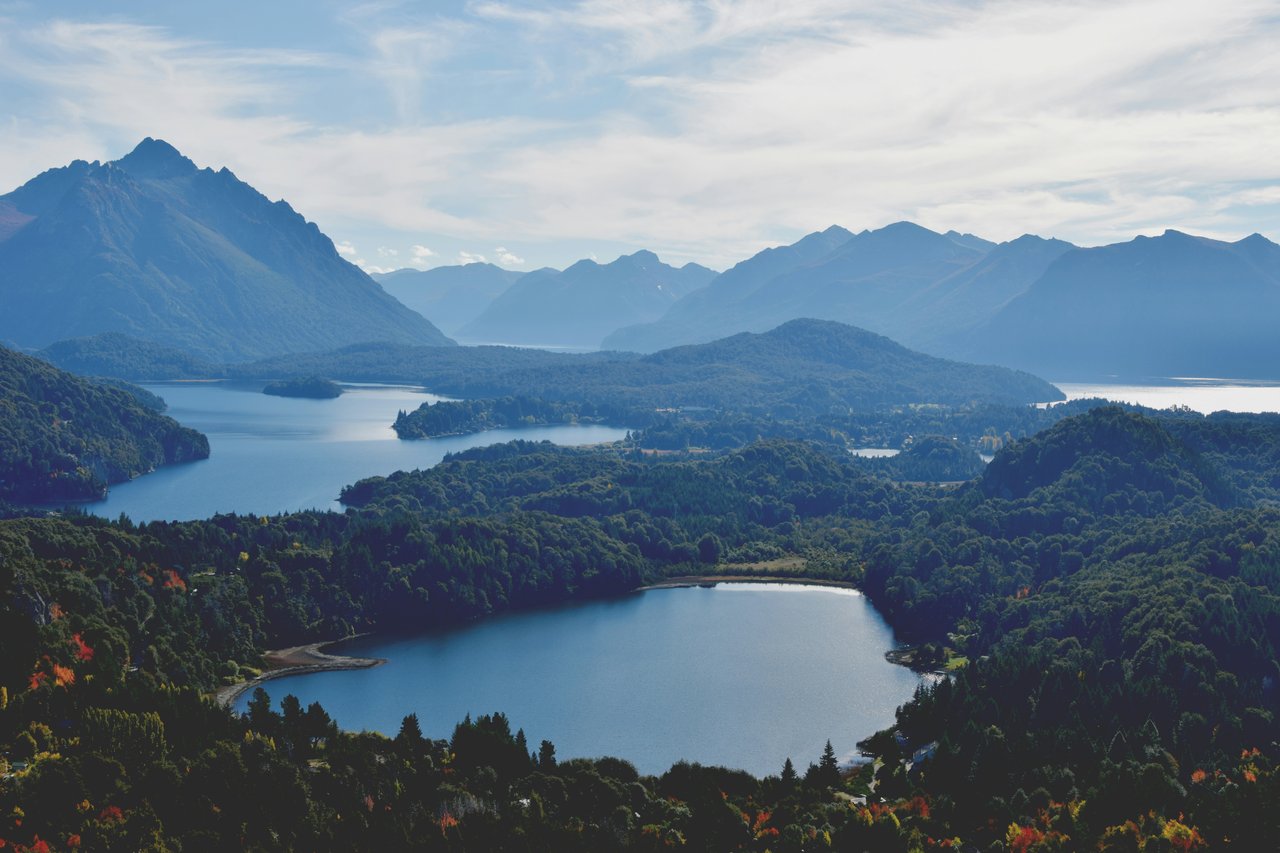Vista panorámica del Circuito Chico de Bariloche con varios lagos y montañas patagónicas en bruma azul superpuestas, paisaje icónico para fotografía