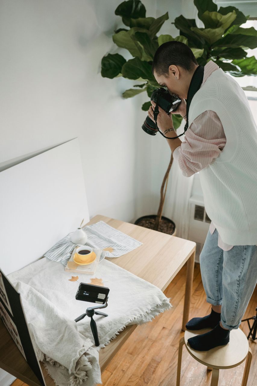 Persona subida a banquito fotografiando flat lay en mesa, ejemplo de fotografía de producto en departamento