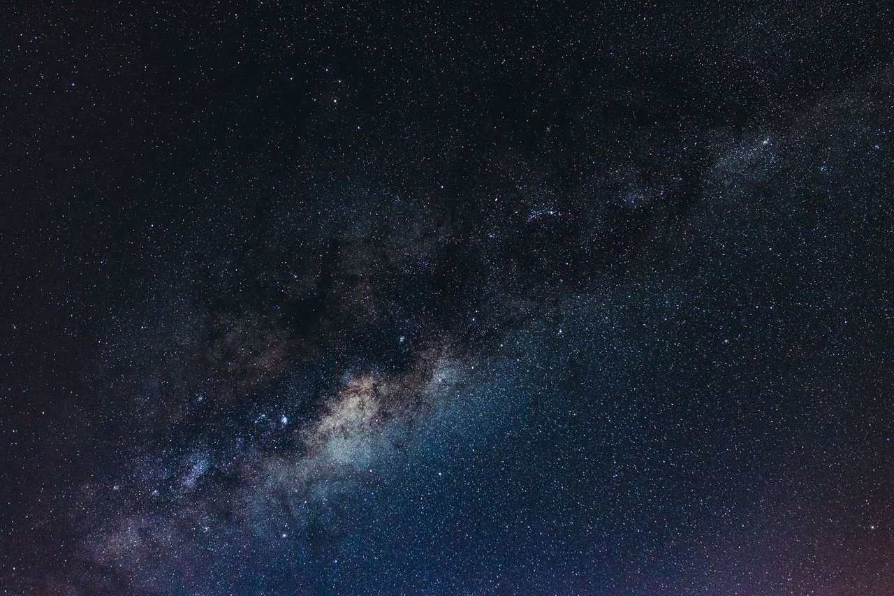 Banda de la Vía Láctea cruzando en diagonal un cielo nocturno, con las nubes de polvo del centro galáctico visibles entre miles de estrellas