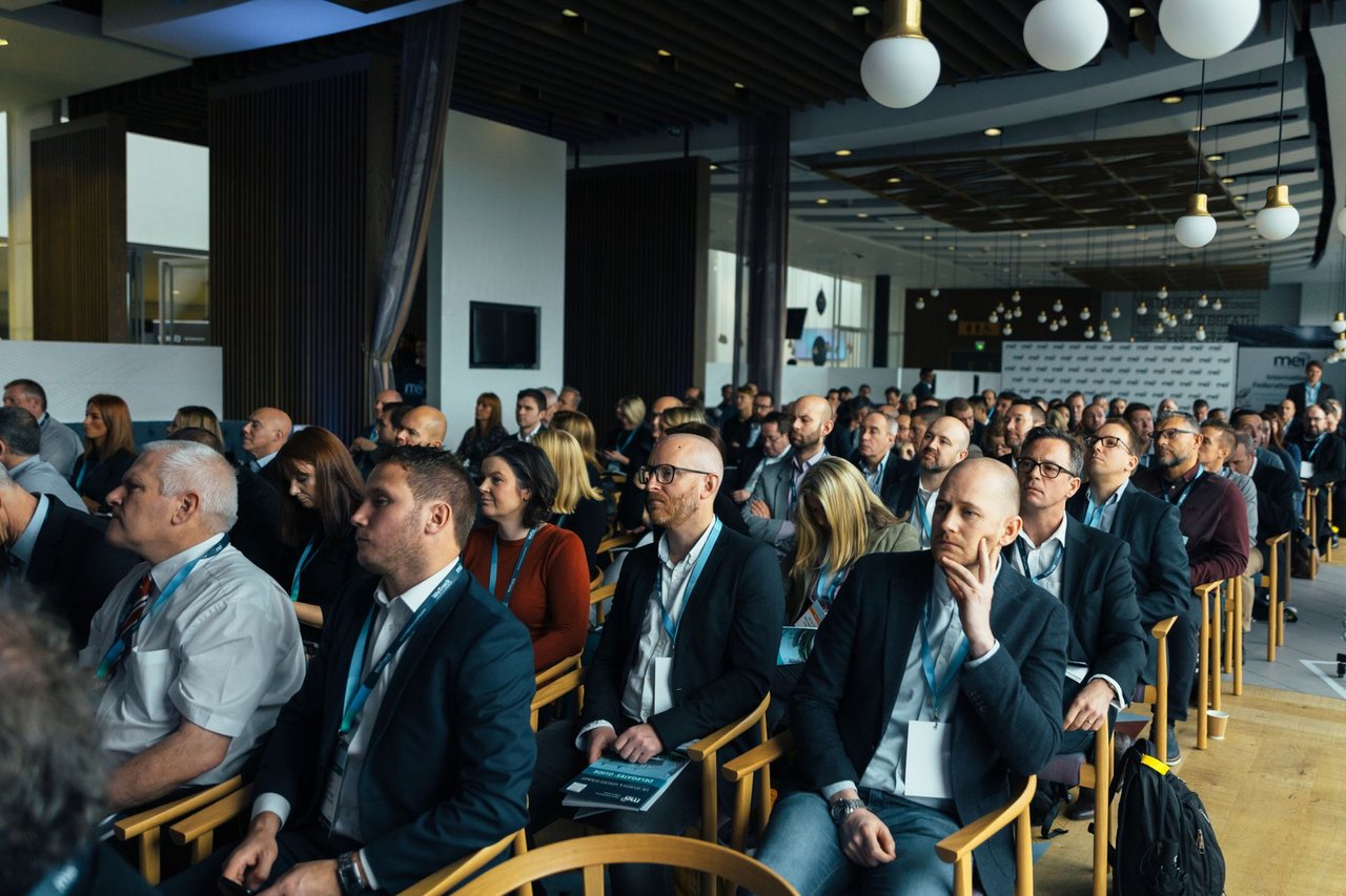 Auditorio lleno de asistentes con credenciales en una jornada corporativa, el tipo de evento donde el precio depende tanto del uso de las fotos como de las horas