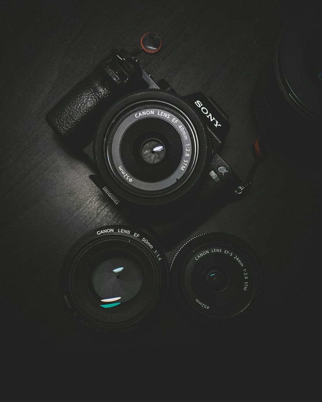 Cámara mirrorless Sony full frame con lente montado y dos lentes fijos al costado sobre una mesa oscura, tono moody que ilustra un equipo profesional de sensor grande